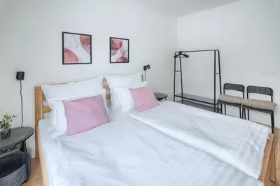 a large bed with white sheets and pink pillows at New Modern Apartment with Parking, near Airport in Prague