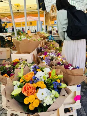 a woman is looking at flowers in a market at Prague Anděl Quiet Comfy apartment in Prague