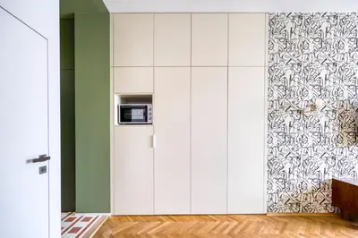 a kitchen with white cabinets and a green wall at Boutique Studio just 5 min from Wenceslas Square by Gravity Prague in Prague