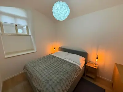 a small bedroom with a bed and a chandelier at ChlumovaNest Apartment in Žižkov, close to the city center in Prague