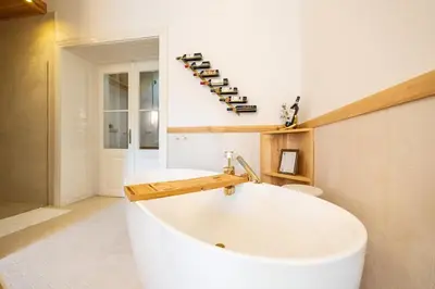 a large white tub in a bathroom with a shelf of wine bottles at Luxury Design Apartment Palackého Residence in Prague