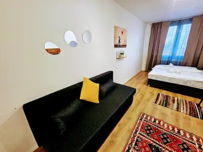 a living room with a black couch with a yellow pillow at PRIVATE GARDEN 2BR PRAGUE APARTMENT for Business & Leisure, FREE PARKING & Gym, by LIVE-INN 2 in Prague