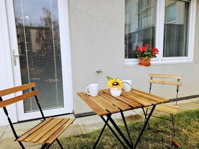 a wooden table with two chairs and flowers on a porch at PRIVATE GARDEN 2BR PRAGUE APARTMENT for Business & Leisure, FREE PARKING & Gym, by LIVE-INN 2 in Prague