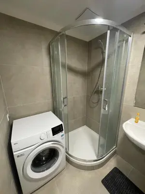 a shower with a washing machine in a bathroom at Newly built Studio in Prague Near Metro Haje in Prague