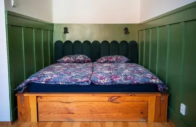 a bed in a green room with a wooden dresser at Cosy apt in vibrant area 2 metro stops from Prague's hisorical centre in Prague
