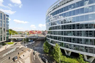 a tall glass building in a city with a street at My Mozart apartments in Prague