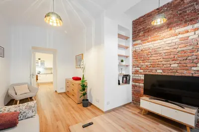 a living room with a brick wall and a flat screen tv at Apartmán 1min River Dancing House in Prague