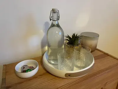 a bottle and glasses on a wooden table at 1Room in Family Apartment Barrandov in Prague