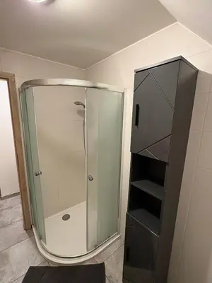 a shower with a glass door in a bathroom at Moderní podkrovní garsonka s hezkým výhledem in Prague