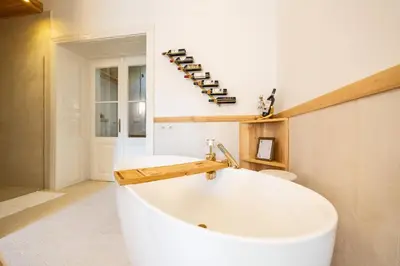 a large white tub in a bathroom with a shelf of wine bottles at Luxury Design Apartment Palackého Residence in Prague