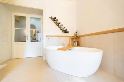 a large white tub in a bathroom with wine bottles at Luxury Design Apartment Palackého Residence in Prague