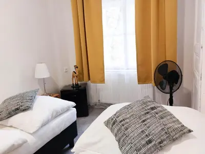 a bedroom with two beds and a window with yellow curtains at Boutique Hotel Milady H in Prague