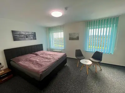 a bedroom with a bed and two chairs in it at Hotel CAVOK letiště Příbram in Drásov