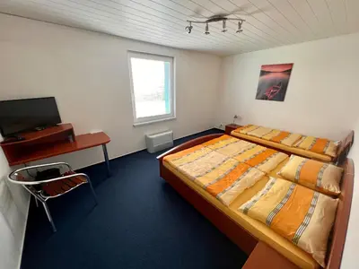 a bedroom with a bed and a desk and a television at Hotel CAVOK letiště Příbram in Drásov