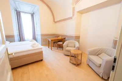 a bedroom with a bed and a chair and a table at Zámek v Kostelci nad Černými lesy in Kostelec nad Černými Lesy