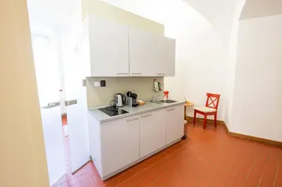 a kitchen with white cabinets and a red tile floor at Zámek v Kostelci nad Černými lesy in Kostelec nad Černými Lesy