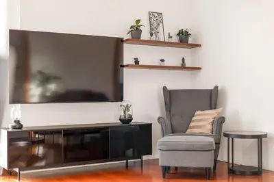 a living room with a large flat screen tv and a chair at Skyline 127m Residence with Terrace - Prague Castle View in Prague