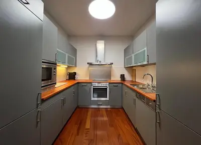 a kitchen with stainless steel appliances and wooden floors at Skyline 127m Residence with Terrace - Prague Castle View in Prague