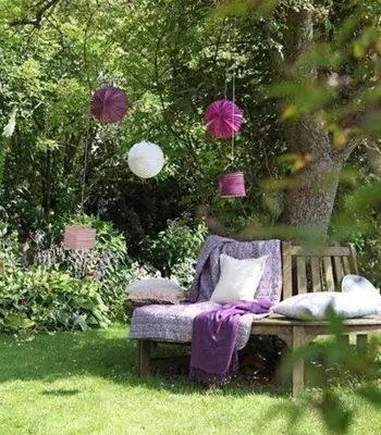 a chair sitting in the grass under a tree at Honey Gardens venkovský apartmán v přírodní zahradě in Oleška