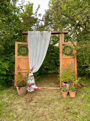 a wooden gate with a curtain and potted plants at Honey Gardens venkovský apartmán v přírodní zahradě in Oleška