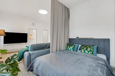 a bedroom with a blue bed and a tv at Skyline 57m Family Suite with Terrace - Prague Center in Prague