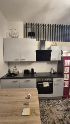 a kitchen with white cabinets and a wooden table at Prague 1 Apartment Nekázanka in Prague
