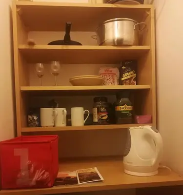 a kitchen shelf with cups and dishes and a blender at Bed in shared dormitory near the city centre in Prague