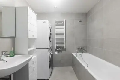 a bathroom with a tub and a sink and a refrigerator at Prague apartment with balcony in Prague