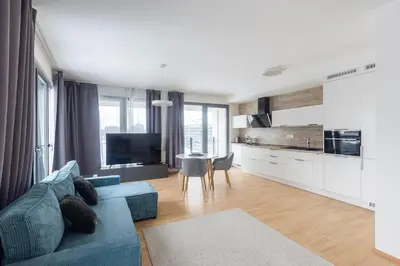 a living room with a blue couch and a kitchen at Prague apartment with balcony in Prague