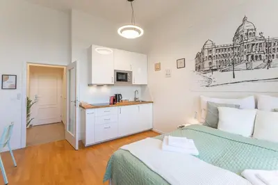 a white bedroom with a bed and a kitchen at Newly renovated apartment next to the National Museum in Prague