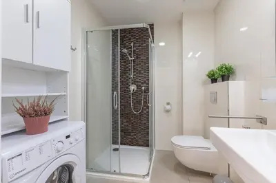 a bathroom with a washing machine and a toilet at Newly renovated apartment next to the National Museum in Prague