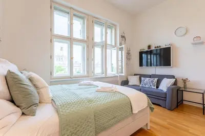 a bedroom with a bed and a couch and a tv at Newly renovated apartment next to the National Museum in Prague
