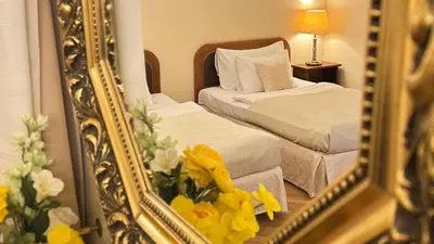 a mirror reflecting a bedroom with two beds and yellow flowers at Fleur De Lis Hotel in Prague