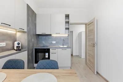 a kitchen with white cabinets and a table and chairs at Apartment near the subway with kitchen and terrace in Prague