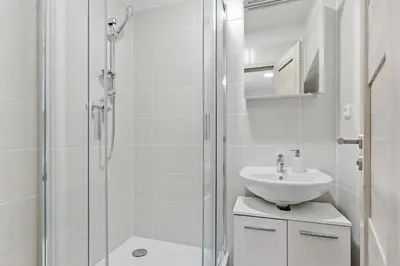 a white bathroom with a shower and a sink at Apartment near the subway with kitchen and terrace in Prague