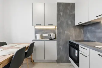 a kitchen with white cabinets and a table with chairs at Apartment near the subway with kitchen and terrace in Prague