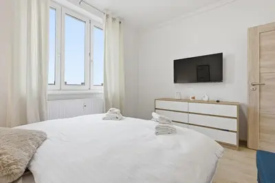 a white bedroom with a bed and a tv at Apartment near the subway with kitchen and terrace in Prague