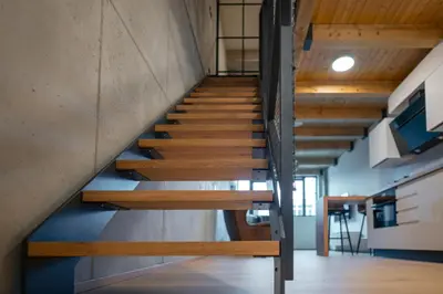 a wooden staircase in a room with a kitchen at Prague Design Loft Kolbenova, Metro, Parking in Prague