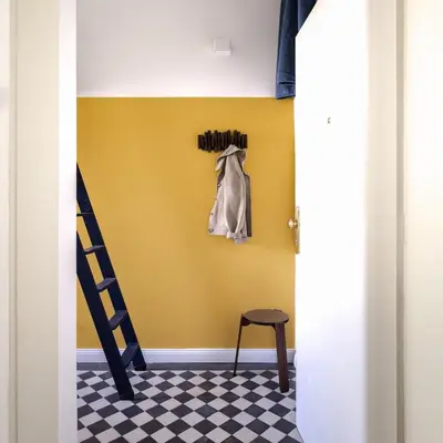 a room with a yellow wall and a ladder and a stool at Bohemian Mystery by Prague Castle in Prague