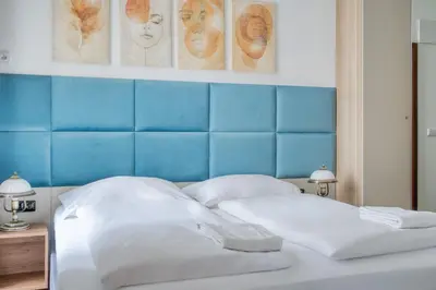 a bed with a blue headboard and two white pillows at Royal Vineyards Apartment in Prague