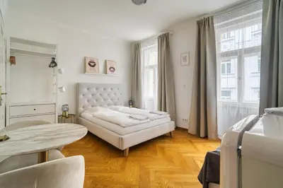 a white bedroom with a bed and a table at Grébovka Parkside Apartment by Rentez in Prague