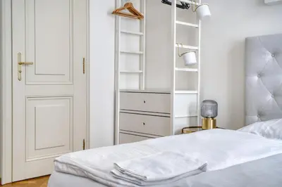 a white bedroom with a bed and a closet at Grébovka Parkside Apartment by Rentez in Prague