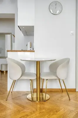 a dining table with white chairs and a clock on the wall at Grébovka Parkside Apartment by Rentez in Prague