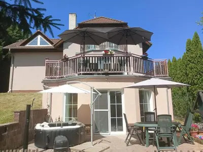 a house with a balcony and a tub with a table and chairs at Holiday Home Komfortvilla in Prag- Hallenbad- Whirlpool- Sauna by Interhome in Vranov