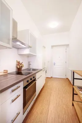 a kitchen with white cabinets and a wooden floor at Apartment Paradies-Wohnung by Interhome in Prague