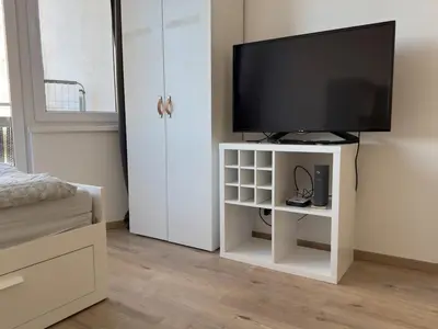 a television on a white stand in a bedroom at Smart Studio for Work & City Exploring in Prague