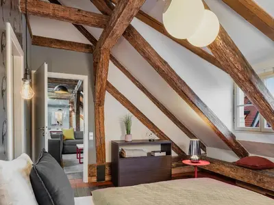 a bedroom with wooden ceilings and a bed and a table at Three Bedroom Apartment with terrace Kepler-4 Art in Prague