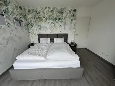 a bedroom with a bed with white sheets and floral wallpaper at Villa with Terrace & private garden 30 min to Prague Center