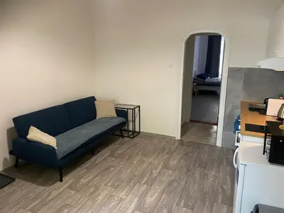 a living room with a blue couch and a hallway at Ground Floor Den in Prague