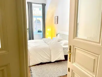 a bedroom with a bed with white sheets and a window at Prague apartment 3 minutes from historical town in Prague